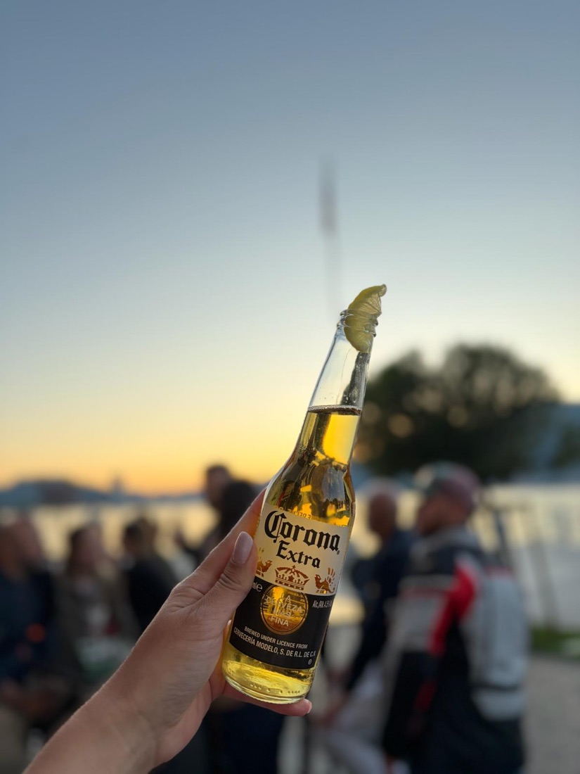 Una birra con lime alzata al tramonto sul lago