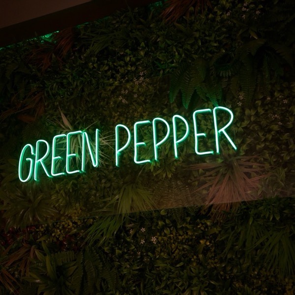 L'insegna al neon Green Pepper sulla parete verde